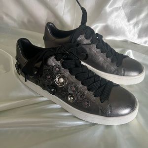 Coach grey metallic leather sneaker with flower accents.